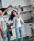 A contemporary kitchen with a couple dancing and a child watching, highlighting a lively family moment.