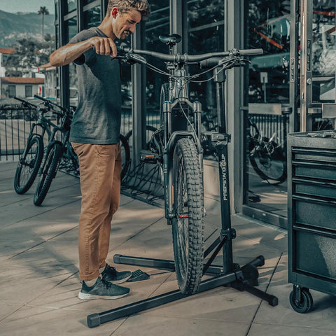 Man using Lift-Assisted Foldable Bike Repair Stand For E-Bikes With Foot Pedal Hydraulic Lift Rotating Clamp Head Reinforced Support