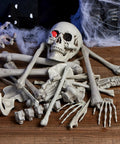 28 Piece Skeleton And Skull Halloween Decor Kit with bones, skull, and hand props on wooden background for spooky decoration.