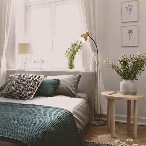 Dimmable Floor Lamp With Sturdy Base For Over Chair Reading in a bedroom, brass finish, providing ambient light next to a bed with cushions.