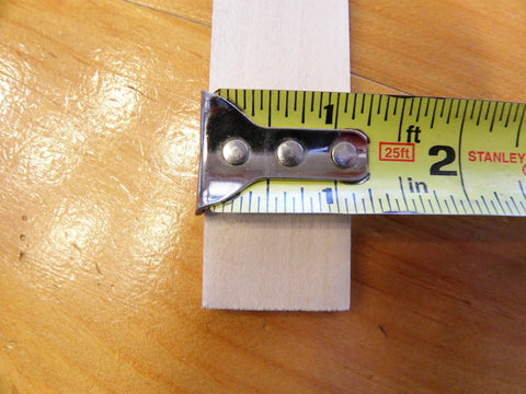 Close-up of American-Made Basswood Paint Stir Sticks 21 Inch Bulk 250 Count with measuring tape showing width