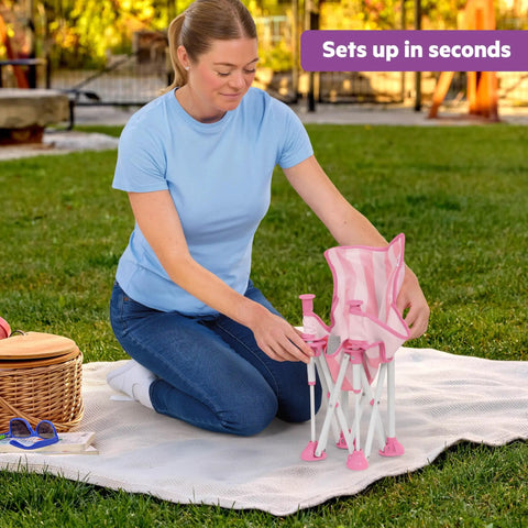 Woman setting up Pop N Sit Cabana Baby Beach Portable Booster Chair with UPF Canopy Removable Tray, pink, on a picnic blanket.