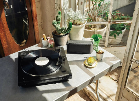Audio-Technica Black Belt Drive Turntable features in a sunlit room on a metal table with potted plants.