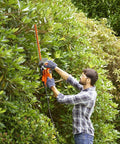 Man using Heavy Duty Electric Hedge Trimmer With 420 Watt Motor And 45CM Cutting Blade for trimming bushes in garden.