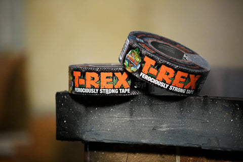 Two rolls of Ferociously Strong Duct Tape One Point Eight Eight Inch By Thirty Five Yard Dark Gunmetal Gray on a brick surface.