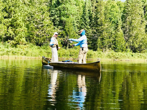 Two people fishing on a canoe with a Hydrodynamic Canoe Stabilizer Float Kit With Gray Floats Adjustable Universal Receiver Fit Low Drag Stability