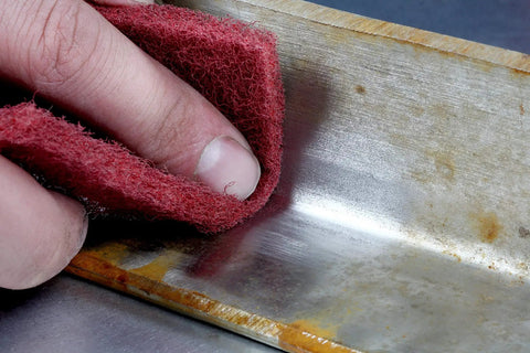 Hand using Roll A VFN 6 Inch By 30 Foot Pro Grade Abrasive Pad Roll for metal finishing and scuffing on metal surface