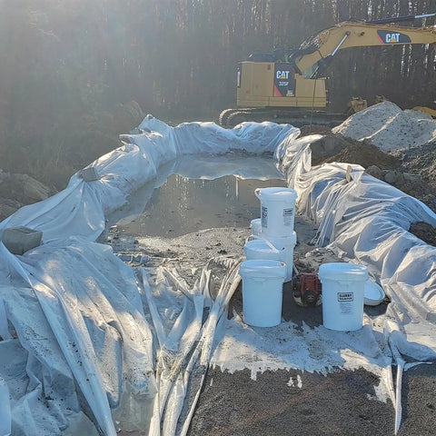 Construction site using Liquid Lock Slurry Absorbent Powder in 5 gallon pail with scoop for solidifying liquid waste