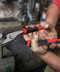 Person using 6.5 Inch Slip Joint Pliers with Groove Joint Function in workshop, demonstrating heavy duty steel construction.