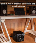 Compact Studio Subwoofer With ARC X Auto Calibration And 25 Hz Deep Bass, 6.5 Inch Driver under table with monitor setup