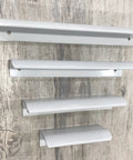 Four white arc edge drawer pulls displayed in varying sizes on a wooden surface. Six Pack White Arc Surface Drawer Pulls For Furniture Cabinets Edge Mount Hidden Cabinet Handles With 64 Millimeter Hole Diameter 3.15 Inch Length Cylindrical Space Aluminum Smooth Safe Edge Available In Multiple Aperture Sizes From 32 To 256 Millimeters
