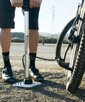 Cyclist using Bike Floor Pump With Industrial Gauge, Durable Aluminum Barrel Up To 160 Psi, 9 Inch Steel Base on gravel road