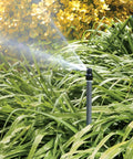 No Fuss Shrub Head Sprinkler With Quarter Pattern Spray Nozzle For Outdoor Gardens And Landscaping  spraying water on lush green grass.