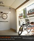 Man fixing bike in garage lit by Six Pack Of Twist Cfl Light Bulbs Giving Off Cozy Soft White 2700K Glow With 1600 Lumens Brightness