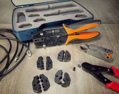 Pro Grade All In One RF Coax Tool Kit with quick-change crimper, cutter, stripper, and five interchangeable die sets displayed on table.