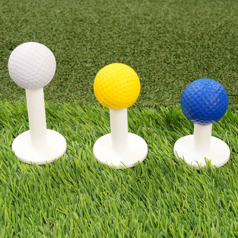 Three colorful golf practice balls on tees on green grass, showing variety in golf training accessories