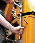 Grease joint rejuvenator kit used on yellow construction equipment; technician holds a long metal rod with a socket