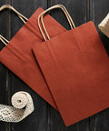 Red Kraft Paper Bags With Handles 16x6x12 Inches Pack Of 250 150 GSM on a dark wooden background with lace ribbons