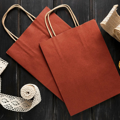 Red Kraft Paper Bags With Handles 16x6x12 Inches Pack Of 250 150 GSM on a dark wooden background with lace ribbons