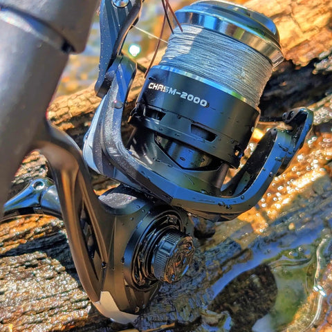 Close-up of a loaded spinning reel with 10lb braided line, CNC aluminum spool, knurled center, black silver finish, and 7 plus 1 bearings.