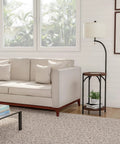 Living room with Go-To Space Saving Floor Lamp With End Table And USB Port beside a beige sofa against a window.