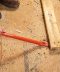 Person using 30-Inch Steel Wrecking Bar Heavy Duty Demolition Pry Tool for Contractors and DIY Pros Built Tough for Industrial and Home Use Meets ANSI and ASME Specs to lift a wooden board.