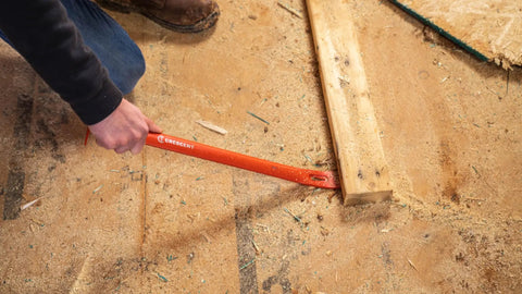 Person using 30-Inch Steel Wrecking Bar Heavy Duty Demolition Pry Tool for Contractors and DIY Pros Built Tough for Industrial and Home Use Meets ANSI and ASME Specs to lift a wooden board.
