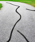 Driveway with 2 Inch Self Adhesive Asphalt Crack Filler Tape For Driveways And Parking Lots applied to repair cracks.