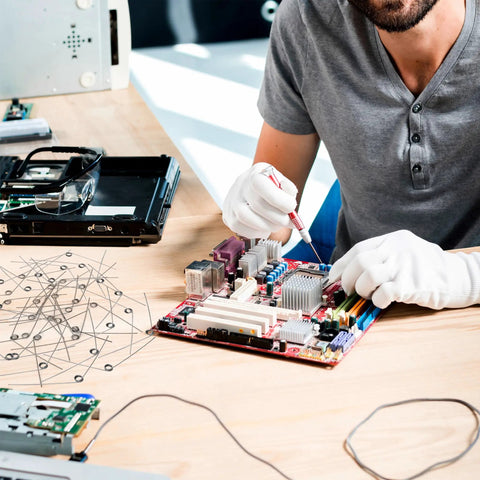 Person in gloves repairing a computer motherboard, using tools; focus on small electronic components on the workspace.