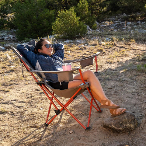 Person relaxing in Deluxe Folding Outdoor Lounge Chair with Insulated Cupholders, steel frame, and recline for comfort outdoors.