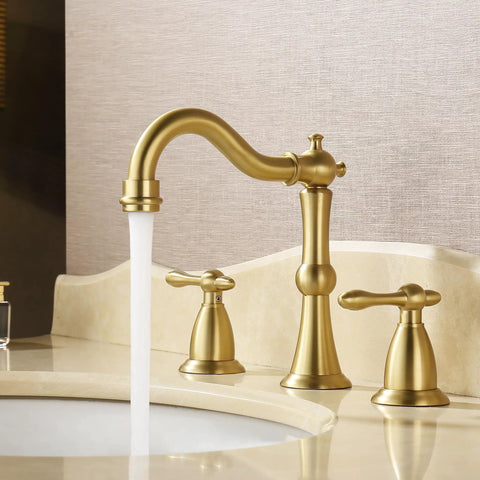 Gold faucet with elegant curved spout and dual handles on beige countertop, flowing water, luxury bathroom setup.