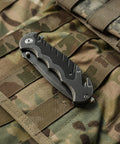Border Guard SWBG10S Folding Knife With 3.1 Inch Serrated Tanto Blade on camo gear, closed position showing aluminum handle and pocket clip