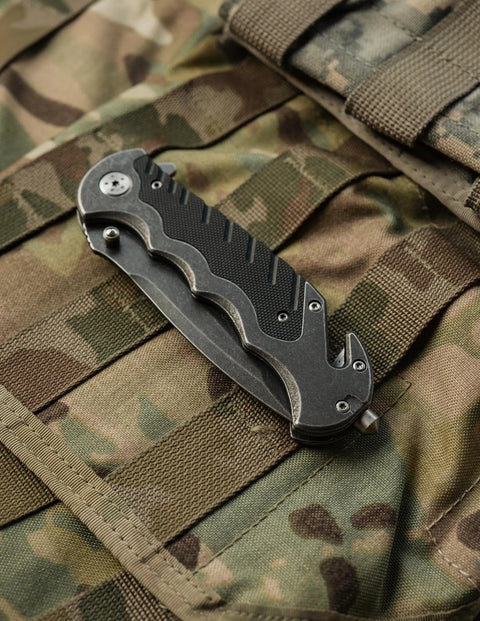 Border Guard SWBG10S Folding Knife With 3.1 Inch Serrated Tanto Blade on camo gear, closed position showing aluminum handle and pocket clip