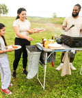 Family using Outdoor Cook Table With Adjustable Height And Foldable Four Foot Work Station at a picnic with cooking accessories