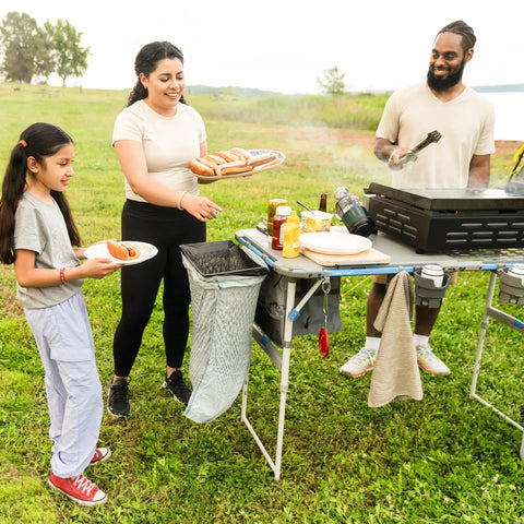 Family using Outdoor Cook Table With Adjustable Height And Foldable Four Foot Work Station at a picnic with cooking accessories