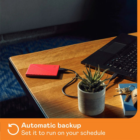 5TB Portable External Hard Drive In Red With Built In Backup Software Ransomware Defense And Password Protection USB 3.1 3.0 Ready Ultra Slim And Durable For On The Go Data Storage connected to laptop on wooden desk