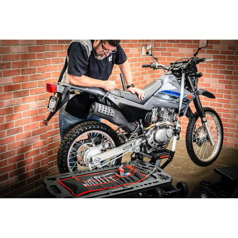 Mechanic using Go-To Motorcycle Tool Kit With Roll Pouch For Roadside And Travel Repairs beside dirt bike with tools visible