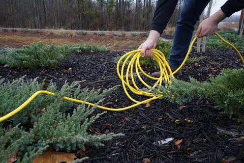 All Purpose Outdoor Extension Cord With A Lit End 50 Feet 12 Gauge 3 Prong SJTW Yellow Weatherproof Vinyl Jacket in use outdoors