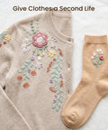 Beige sweater and sock with floral embroidery, showcasing clothing repair and embellishment.