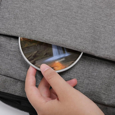 Hand placing 10W Fast Wireless Charger Pad Ultra Slim Portable Charging Station into grey fabric bag pocket