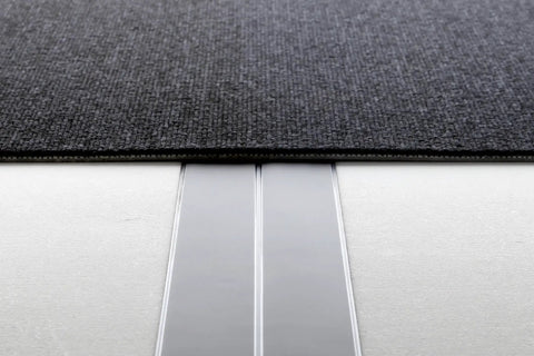 Ultra Flat Extension Cord 20 Foot White Power Cable Featuring Paper Thin Build under a dark rug, showing unobtrusive wiring.