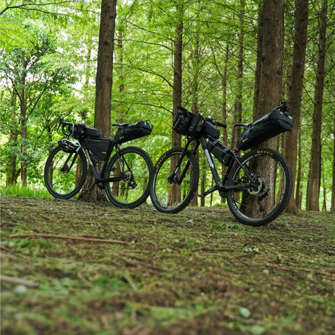 Two bikes with Waterproof Bike Saddle Bag With Expandable 10L And 13L Capacity Under Seat Pouch in forest setting.