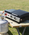 Three Burner Propane Grill And Griddle Combo With Lid, 29,000 BTU Output, on a picnic table, propane tank beside grill