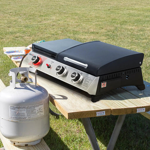 Three Burner Propane Grill And Griddle Combo With Lid, 29,000 BTU Output, on a picnic table, propane tank beside grill