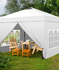 10x10 Pop Up Canopy Tent With Four Sidewalls One Push Setup for Quick No Tool Outdoor Shade Silver Coated Canopy Includes Sandbags Ideal for Parties Events Camping and Beach White, set up on grass with chairs and a table inside, white color.