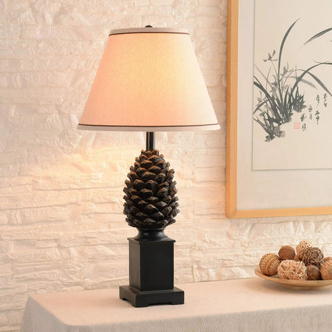Rustic Pinecone Accent Table Lamp In Aged Bronze Finish, 29 Inch Tall With A 15 Inch Tapered Shade on a living room table