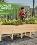 Man watering plants in a 7x2 Ft Raised Garden Bed With 16 Inch Depth And Legs, Drainage Holes, Perfect For Deep Rooted Veggies and Herbs.