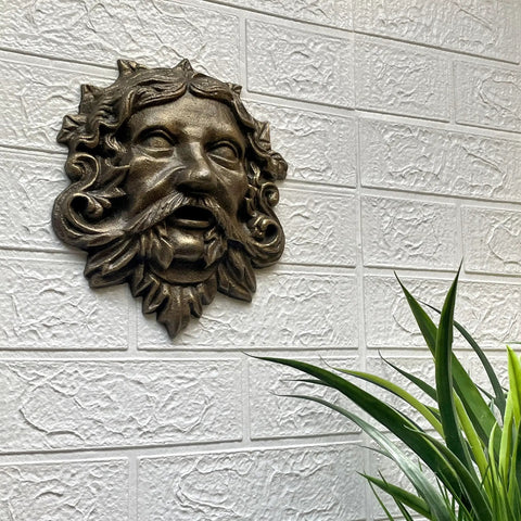 Top Tier Green Man Wall Decor, Slick 9.75 Inch Heavy Duty Cast Iron Plaque, Solid Bronze Finish mounted on textured wall.