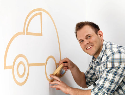 Man applying Masking Tape For Curves Ultra Flexible 19mm By 25m Pro Grade Tape to create car shape on wall.