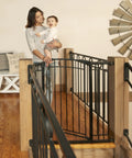 Multi-Use Tall Walk-Thru Baby Gate In Black Metal, Pressure Mount Or Hardware Mount Options, shown at the top of the stairs.